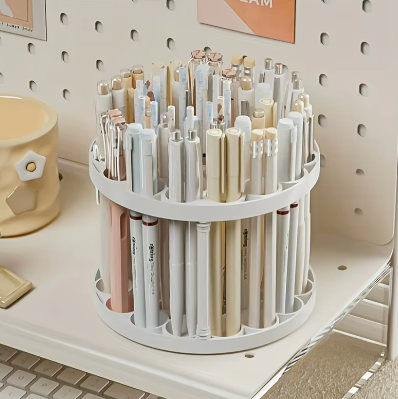 Circular 360° rotating brush holder with multiple compartments filled with pens and brushes on a desk.