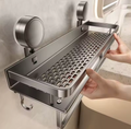 Suction shower caddy mounted on a smooth surface, featuring a perforated shelf design and two large suction cups.