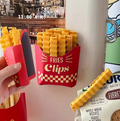 Red container resembling a French fry box holding yellow bag clips, with snacks visible in the background.