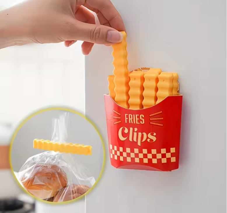 Hand holding a yellow French fry-shaped bag clip with a container of multiple clips in a playful design.