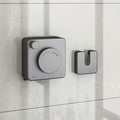 Wall-mounted clothes hanging line installed on a smooth surface with a round dial and hook in neutral gray tones.